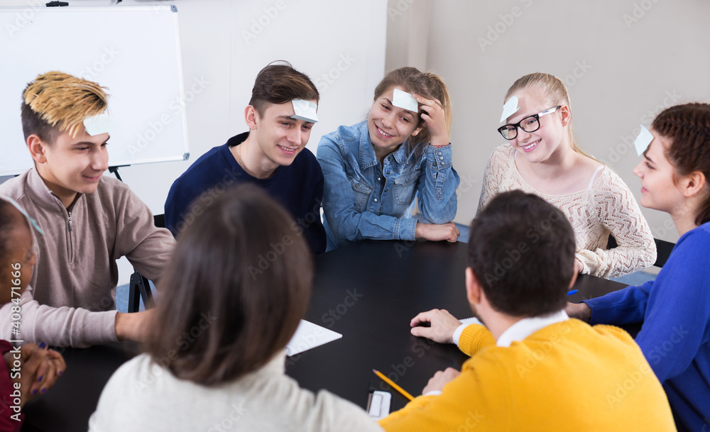 Obraz premium Positive young students playing guess-who game in school