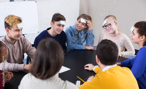 Positive young students playing guess-who game in school