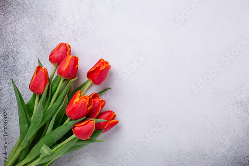 Fototapeta Naklejka Na Ścianę i Meble -  Beautiful red tulips on a light stone table. Spring background. Top view. Copy space - Image
