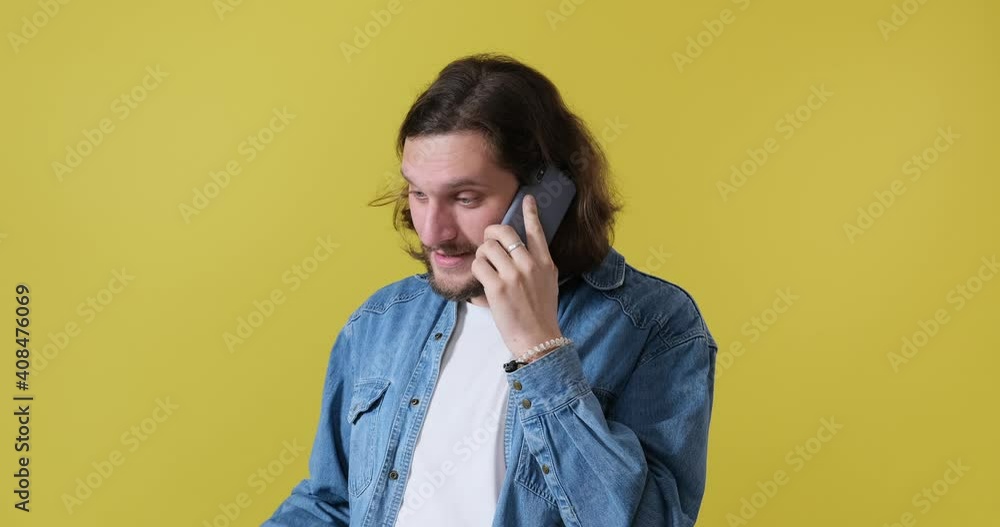 Man in denim jacket talking on mobile phone over yellow background Man in denim jacket talking on mobile phone over yellow background