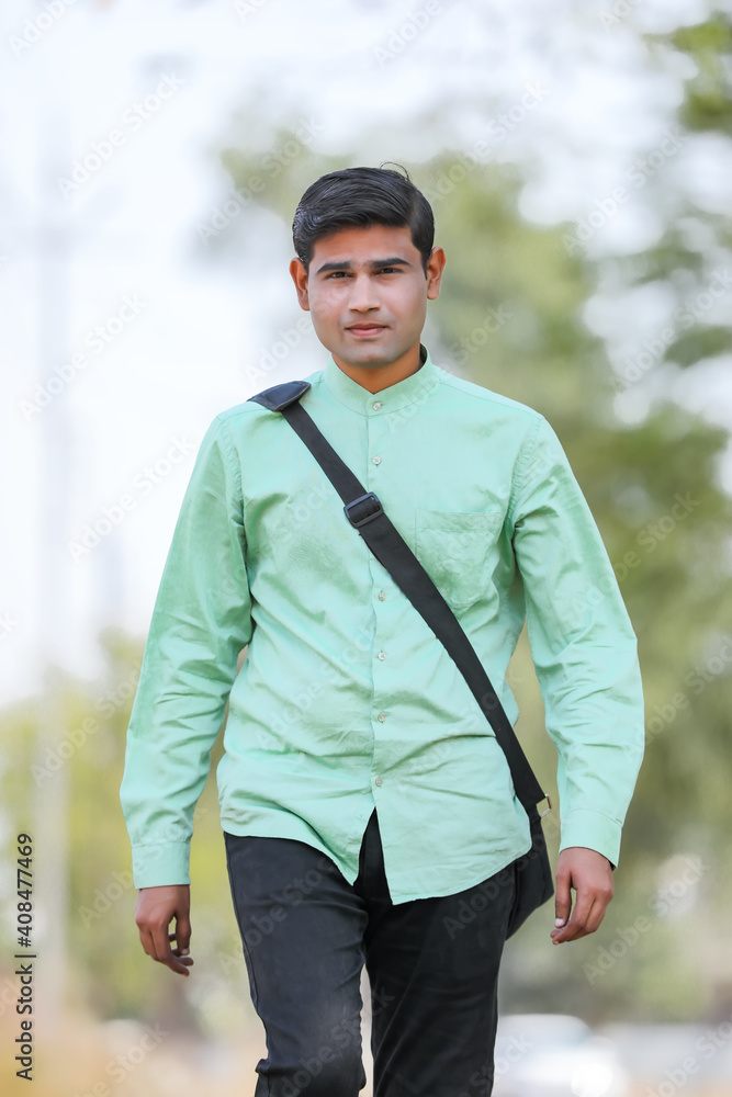 Young Indian male model standing and holding the office bag and giving expression. Young Indian male model standing and holding the office bag and giving expression.