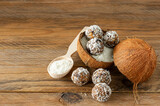 Healthy food concept. Homemade coconut energy balls in cocnut shell on wooden background.