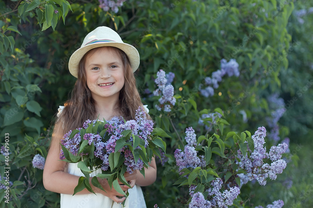 Beautiful girl in straw hat in lilac Garden. Girl with lilac flowers in springtime. Gardening