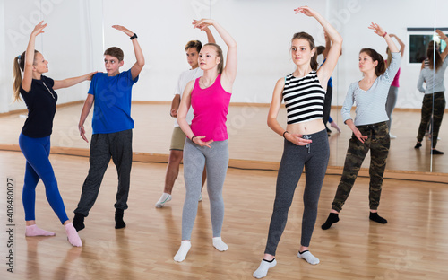 Group of teenage boys and girls training ballet dance in dance hall