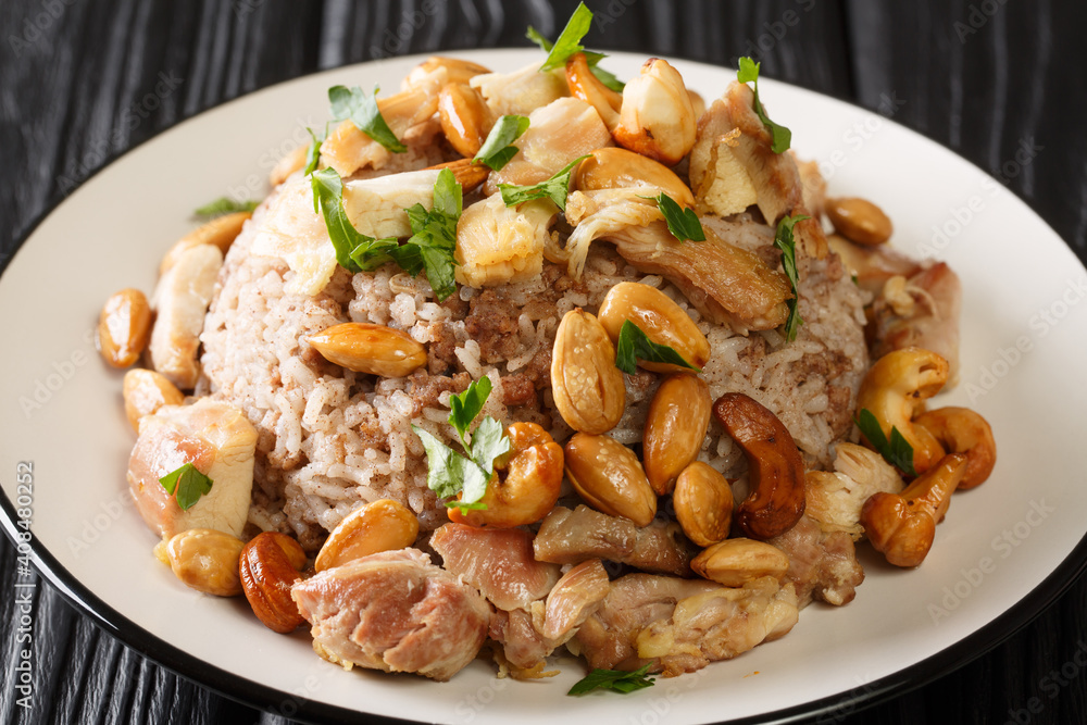 Authentic cinnamon and ground beef rice recipe topped with chicken and nuts close-up in a plate on the table. horizontal Authentic cinnamon and ground beef rice recipe topped with chicken and nuts close-up in a plate on the table. horizontal