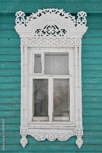 Ornamental window with carved frame on vintage wooden rural house in Nerekhta town, Kostroma region, Russia. Building facade. Russian traditional national folk style in architecture. Russan landmark photo