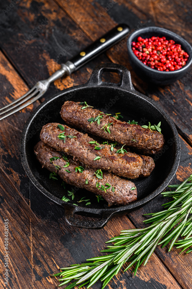 Grilled mince meat  sausages in a pan. Dark wooden background. Top view