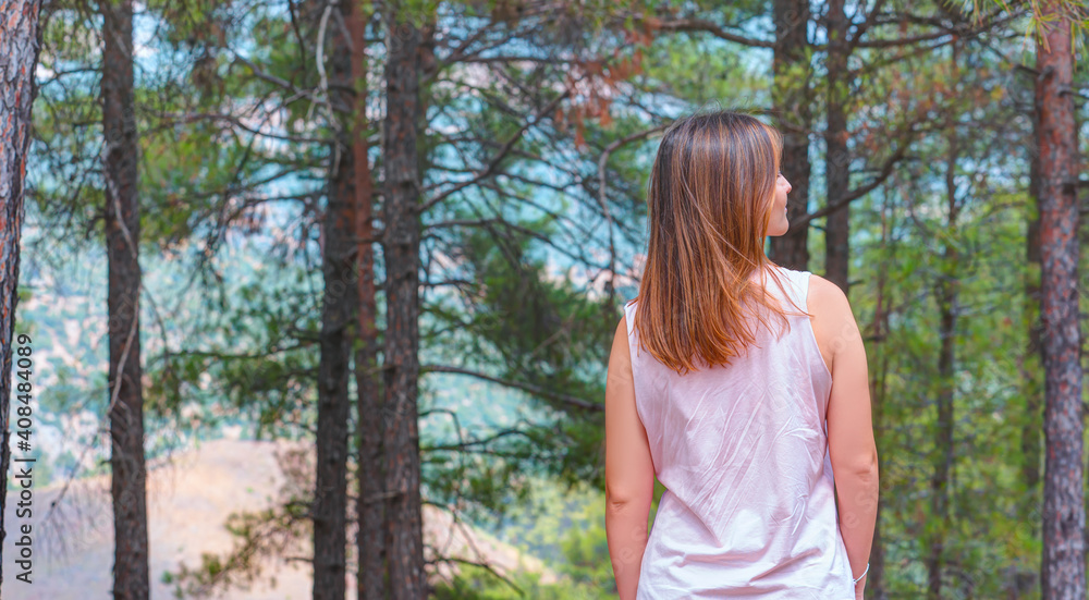 A beautiful young girl stands near an evergreen tree with long green needles A beautiful young girl stands near an evergreen tree with long green needles