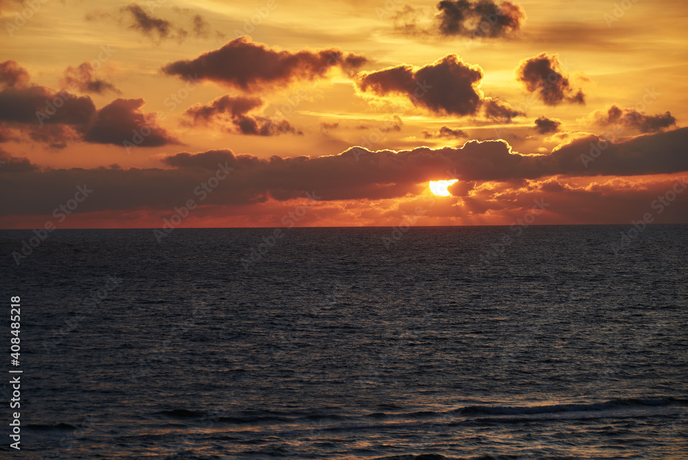dramatic sunset behind clouds over the water of the North Sea dramatic sunset behind clouds over the water of the North Sea