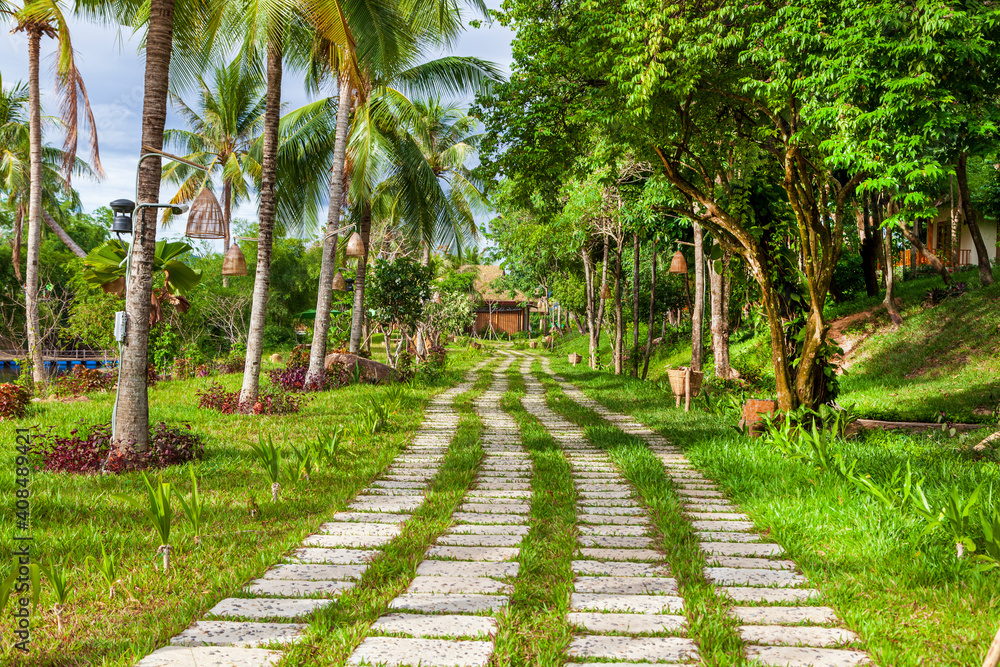 Obraz premium beautiful place for the weekend, Photo of a curved alley of stone bricks in a city park among green spaces