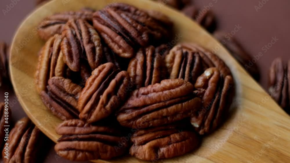 Pecan nut close-up in wooden spoon on bright brown background.Healthy fats. Ingredient of the keto diet Pecan nut close-up in wooden spoon on bright brown background.Healthy fats. Ingredient of the keto diet