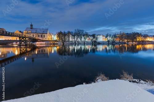 Eiserner Steg and church St. Oswald in Regensburg on the danube river in winter with fresh snow