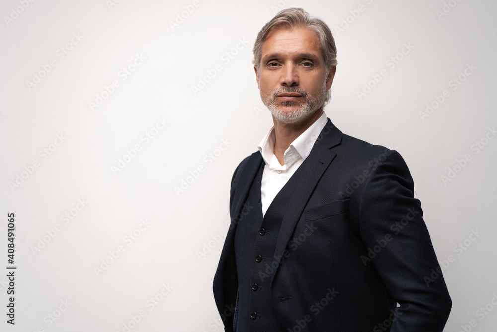 Handsome middle-aged man in suit posing against grey background Handsome middle-aged man in suit posing against grey background
