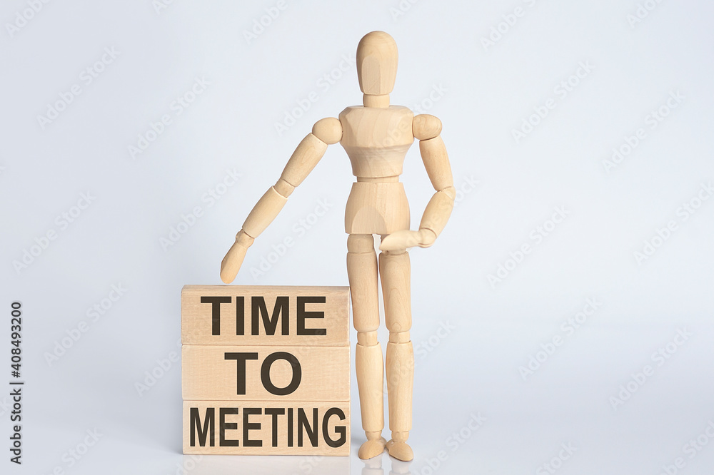 Wooden man shows with a hand text TIME TO MEETING concept on the wooden block Wooden man shows with a hand text TIME TO MEETING concept on the wooden block