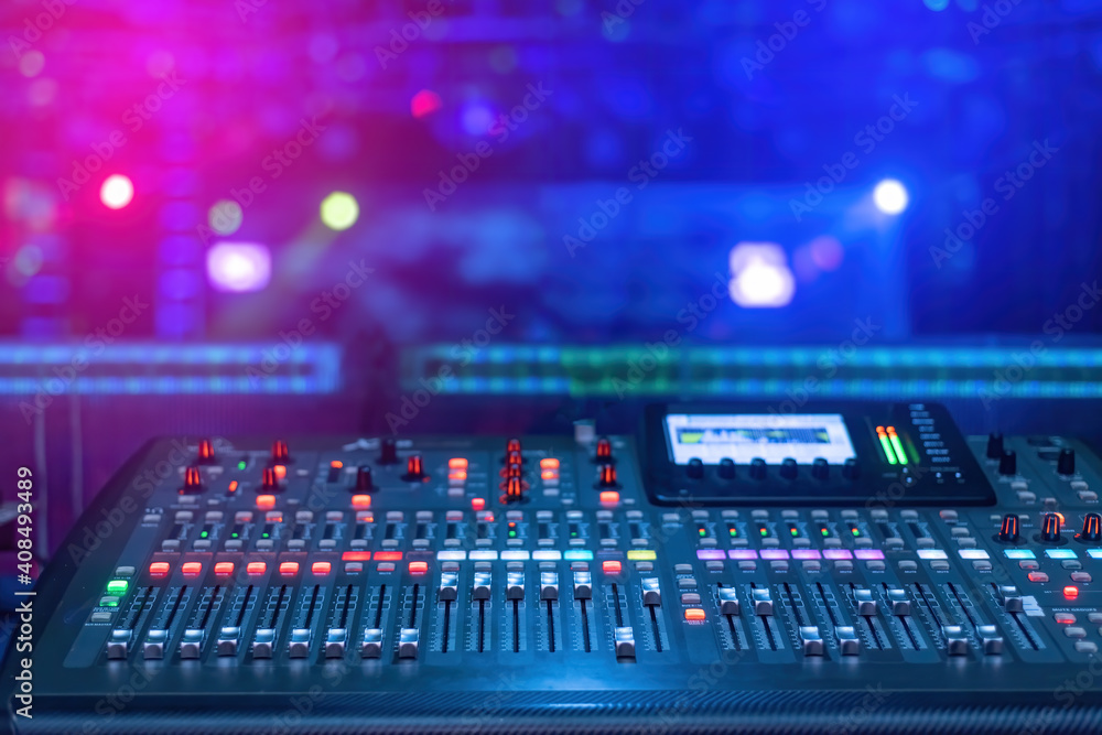 A mixer for mixing music with buttons and screen and a blue and pink background under low light conditions. A mixer for mixing music with buttons and screen and a blue and pink background under low light conditions.
