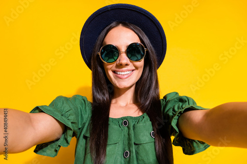 Photo portrait of adorable girl taking selfie smiling isolated on vivid yellow colored background