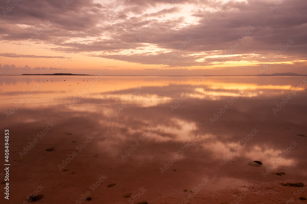 Peaceful sunrise with its colors reflecting in the calm sea at Nakano beach. Iriomote island.