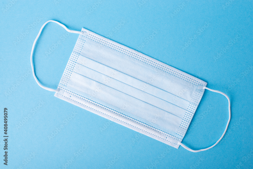 One new disposable medical mask on a blue background. Concept of medicine One new disposable medical mask on a blue background. Concept of medicine