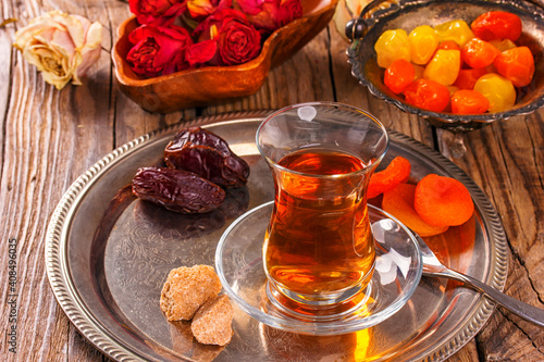 various dried fruits and Turkish tea in Armudu glass on wooden table.