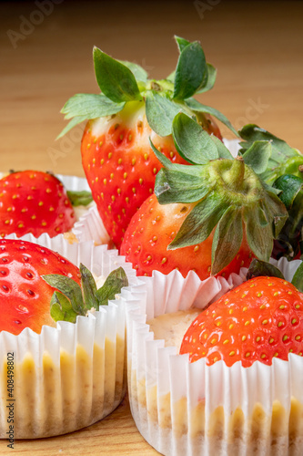 Vertical closeup of the mini strawberry cheesecakes on the wooden table photo