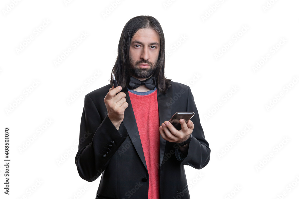 A man with long hair and a beard with an electronic cigarette with sticks and a phone in his hands on a white background. He is wearing a black jacket and a red T-shirt and a bow tie around his neck. A man with long hair and a beard with an electronic cigarette with sticks and a phone in his hands on a white background. He is wearing a black jacket and a red T-shirt and a bow tie around his neck.