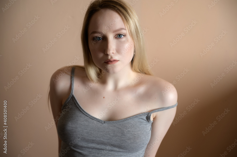 Graceful young woman posing against beige wall. Graceful young woman posing against beige wall.