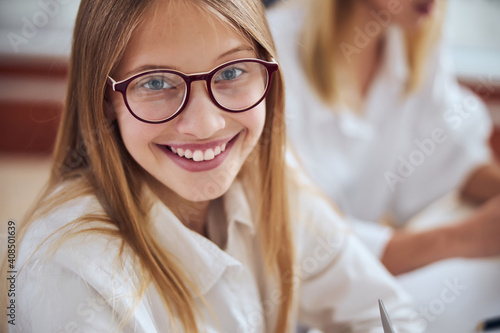 Young blonde female child with cute smile choosing best eyeglass in office ophthalmologist photo