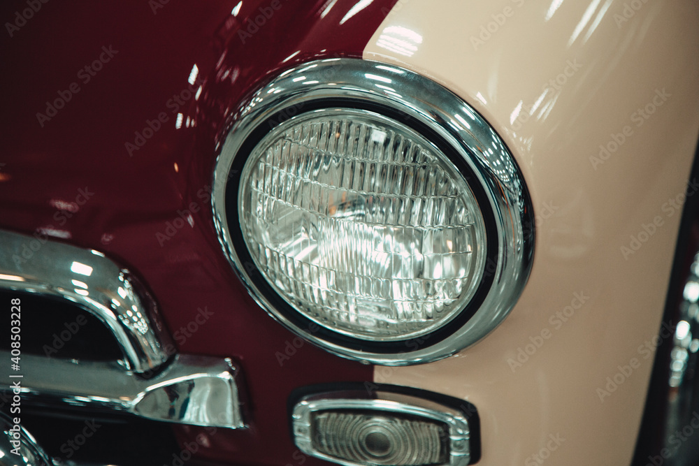 headlights of a retro vintage car in red in a showroom.
