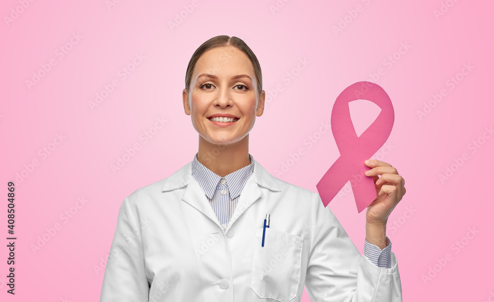 medicine, healthcare and oncology concept - happy smiling female doctor in white coat with breast cancer awareness ribbon over pink background medicine, healthcare and oncology concept - happy smiling female doctor in white coat with breast cancer awareness ribbon over pink background