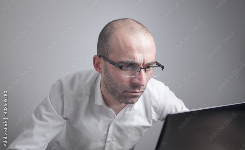 Caucasian man wearing glasses working with laptop. Caucasian man wearing glasses working with laptop.
