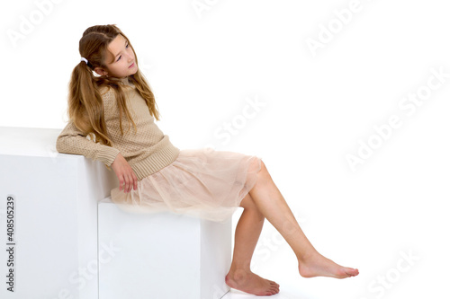 Beautiful girl sitting on a white cube