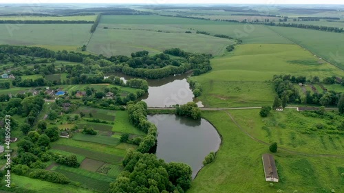 Aerial view of the countryside and the river. A little bridge over the river. Agricultural land and houses