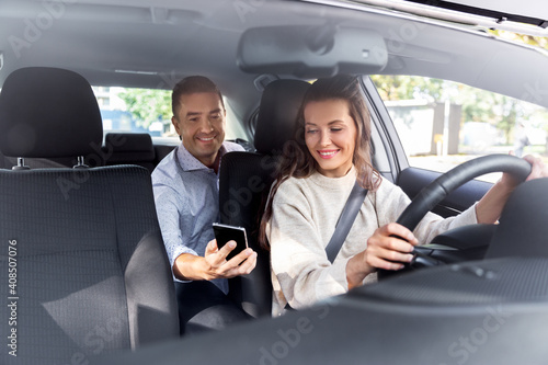 transportation, vehicle and people concept - male passenger showing smartphone to happy smiling female taxi car driver © Syda Productions