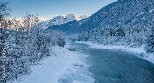 River, surrounded by snow-covered trees and a beautiful mountains in background.