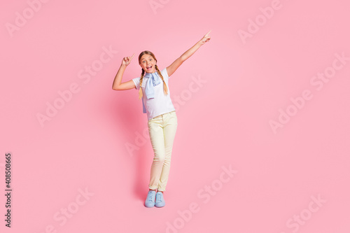 Full length photo of young preteen girl happy smile indicate fingers empty space promo recommend isolated over pastel color background