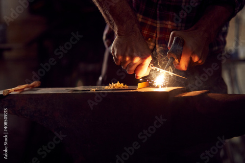 Close Up Of Male Blacksmith Lighting Wood Shavings With Firesteel On Anvil To Light Forge