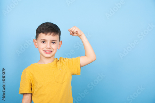 Portrait of cute kid boy showing the muscle of his arm. Power boy