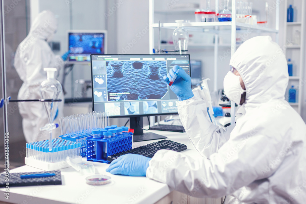 Medicine engineer with face mask and coveall looking at blood samplein lab. Doctor working with various bacteria and tissue, pharmaceutical research for antibiotics against covid19. Medicine engineer with face mask and coveall looking at blood samplein lab. Doctor working with various bacteria and tissue, pharmaceutical research for antibiotics against covid19.