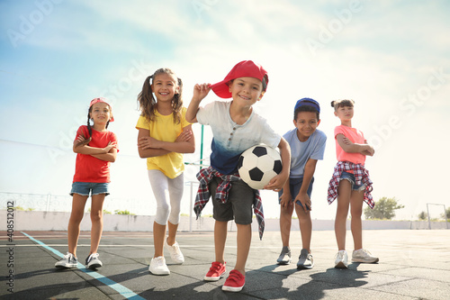 Fototapeta Naklejka Na Ścianę i Meble -  Cute children with soccer ball at sports court on sunny day. Summer camp
