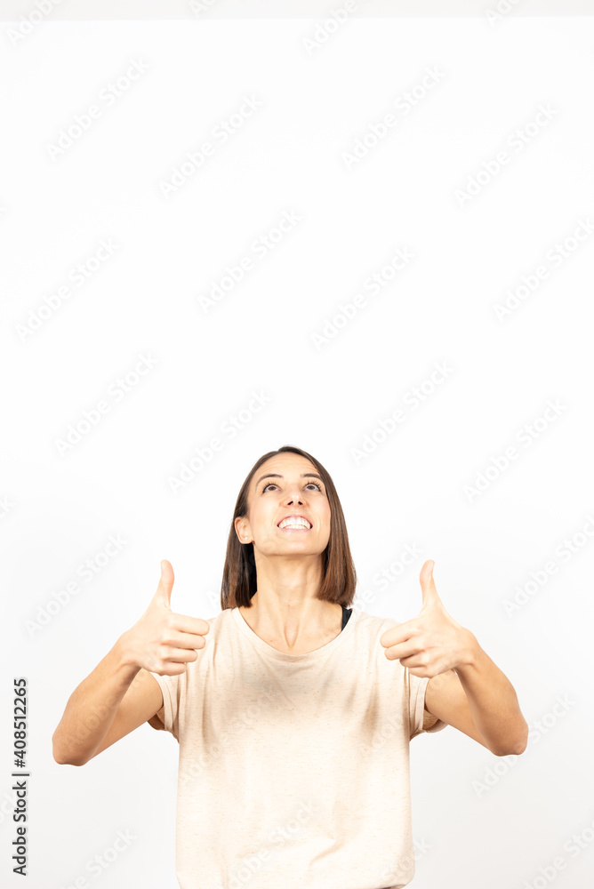 A happy woman with the thumbs up looking up to the white copy space. A happy woman with the thumbs up looking up to the white copy space.