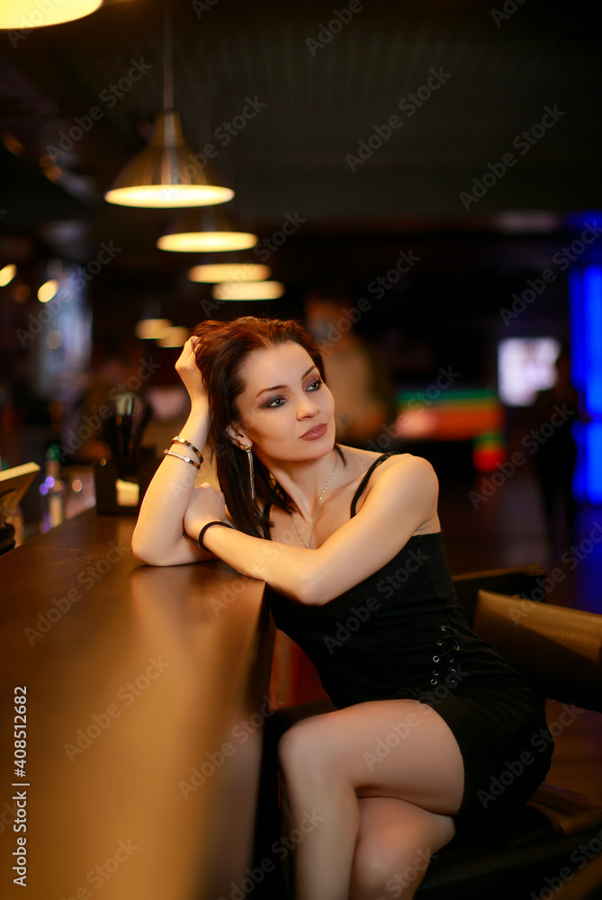 Beautiful brunette woman in evening dress posing near bar alone Beautiful brunette woman in evening dress posing near bar alone