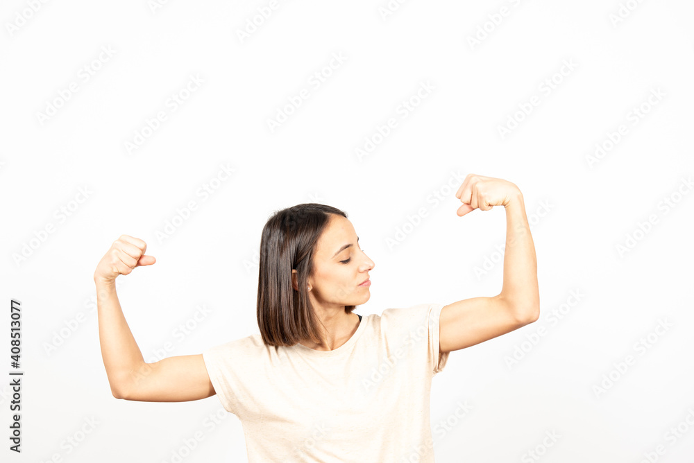 An hispanic fit woman showing her strong biceps isolated on white background with copy space. An hispanic fit woman showing her strong biceps isolated on white background with copy space.