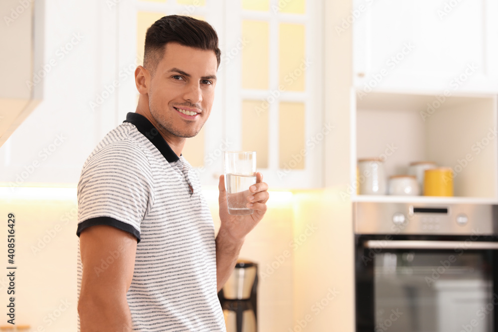 Man holding glass of pure water in kitchen. Space for text Man holding glass of pure water in kitchen. Space for text