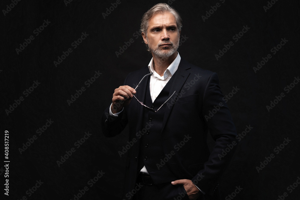 Portrait of a respectable mature man in a suit and sunglasses on a black background. Businessman portrait. Copy space Portrait of a respectable mature man in a suit and sunglasses on a black background. Businessman portrait. Copy space