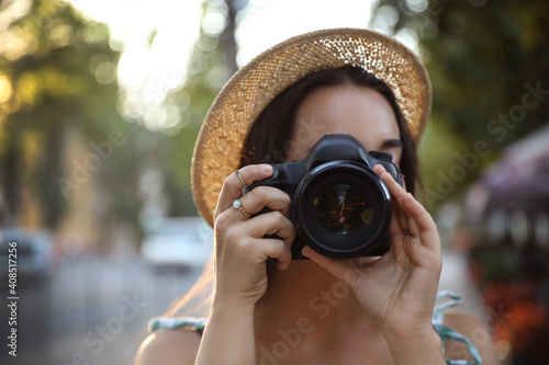 Young photographer taking picture with professional camera outdoors