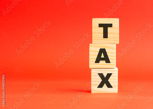 Wooden cubes with word TAX. Wooden cubes on a red background. Free space on the left.