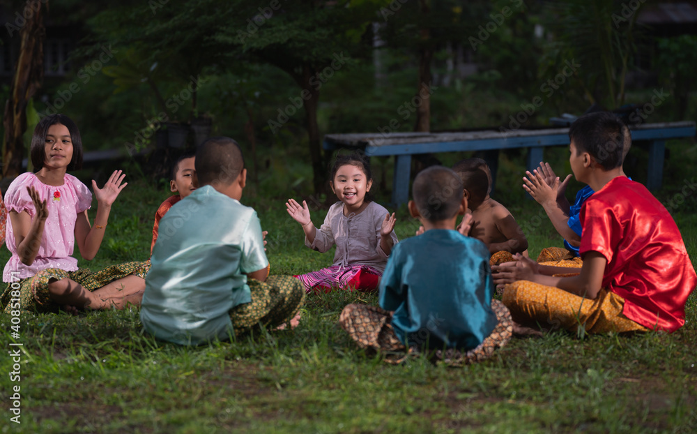 Obraz premium Group of Asian children in traditional costumes playing outdoor activities. local traditional game in Thai culture concept. 
