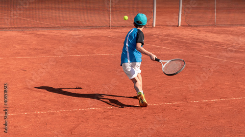 Child on tennis court. Boy tennis player learning to hit forehand . Physical activity and sports education of children. Tennis training at school or club. Background, copy space © Elena