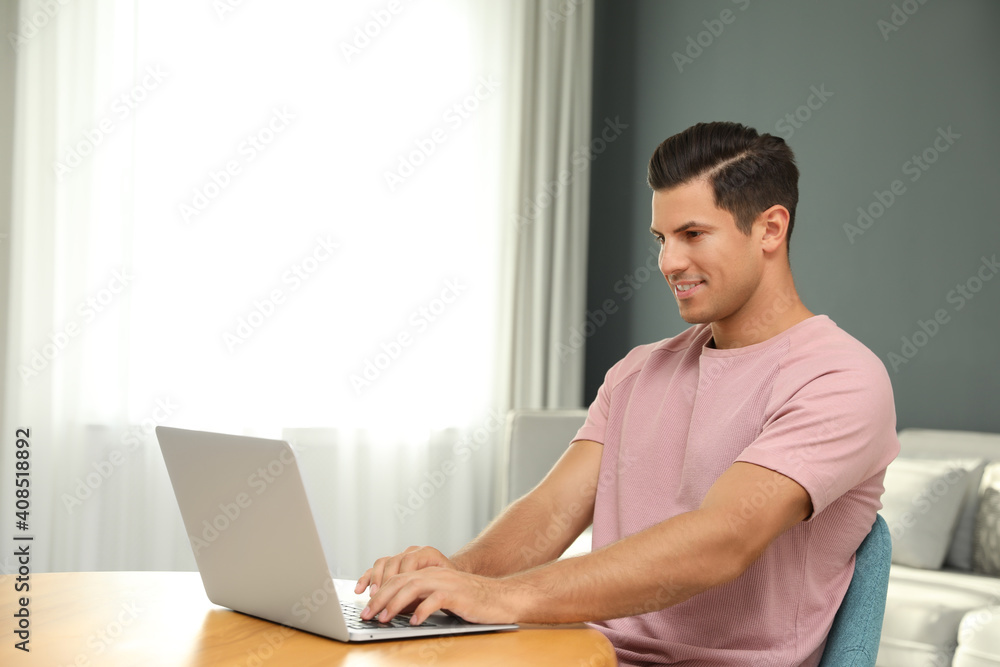 Man using laptop for search at wooden table in living room Man using laptop for search at wooden table in living room