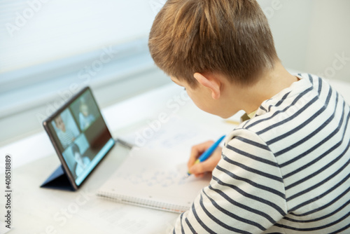 Teenager schoolboy at virtual lesson at home using tablet during homeschooling at pandemic quarantine